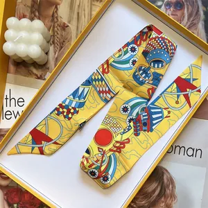 Détail du foulard twilly en soie jaune à imprimé pop-art dans un coffret cadeau