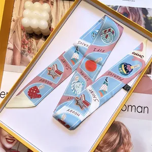 Blue and pink patterned twilly silk scarf with whimsical illustrations in a gift box