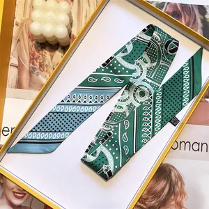 Green silk skinny scarf with geometric patterns in a gift box on a stylish background