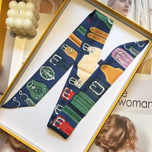 Detail of vintage print twilly scarf with belt motif inside a yellow gift box