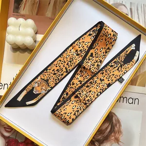 Detail of orange leopard print twilly scarf folded inside a premium yellow gift box