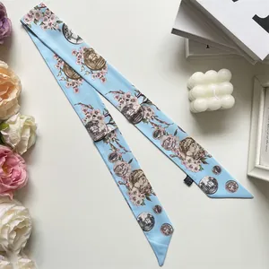 Detailed macro view of light blue twilly silk scarf with floral and coin patterns