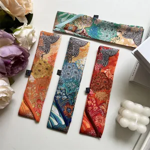 Detail of four faux silk skinny scarves with zebra and tropical floral prints on white surface