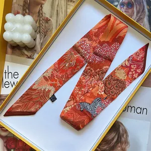 Detail of tropical zebra print silk twilly scarf in premium orange gift box packaging