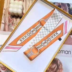 Pink and orange twilly silk scarf with belt print and polka dots on a white tray