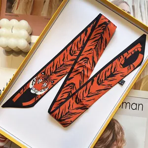 Detailed view of an orange and black tiger print silk twilly scarf with realistic tiger head