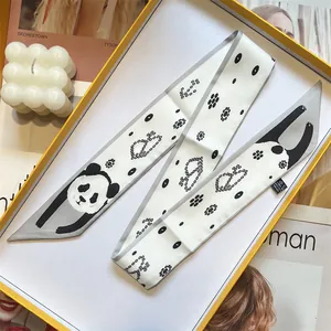 Detail view of panda pattern silk scarf folded in a gift box with a care label