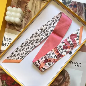 Detail eines Seidengefühl-Schals mit geometrischen Mustern in einer Geschenkbox