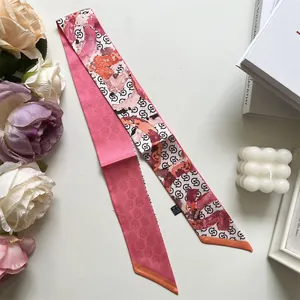 Detail eines künstlerischen rosa Seidenschals, der um Handtaschengriffe gewickelt ist