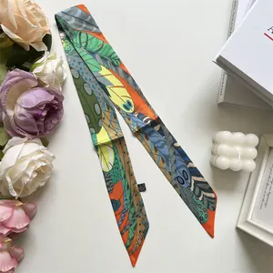 Plano detalle de un pañuelo largo de seda con coloridos motivos de plumas y decoración