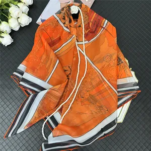 Gros plan sur un foulard en soie orange avec motif Valkyrie et décor floral élégant