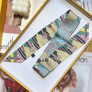Elegant silk twilly scarf with geometric patterns and belt buckle design in a yellow gift box