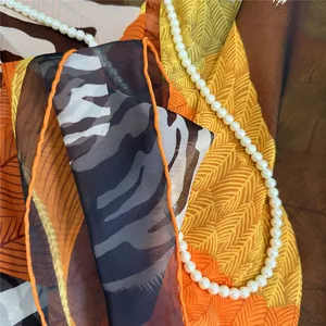 Detail of thin georgette scarf showing orange rolled hem and abstract animal print
