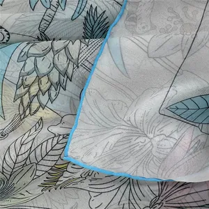 Detail van zijden sjaal met tropische bloemenprint en lichtblauwe handgerolde afwerking