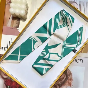 Sciarpa di seta verde con motivi geometrici presentata in una confezione regalo bianca