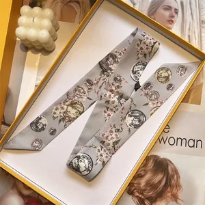 Elegant grey silk skinny scarf with pink cherry blossoms and coin motifs in an orange gift box