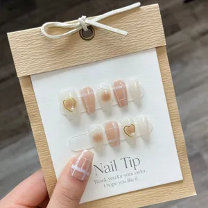 Handgefertigte Kunstnägel in Creme und Braun mit Goldherz-Perle und Karomuster