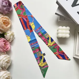 Detail eines Seidengefühl-Twilly-Schals mit Blumendruck um den Taschengriff gewickelt