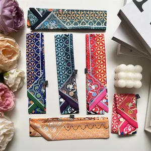 Detail of colorful printed twilly scarves with 100% polyester wash label on white surface