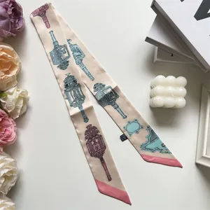 Detail van de champagne satijnen twilly sjaal met vintage patronen op witte tafel