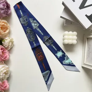 Detail van een marineblauwe smalle zijden sjaal op witte basis met decoratieve items