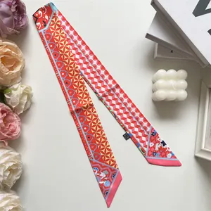 Detail of red floral long skinny scarf with wash care label and lifestyle decor