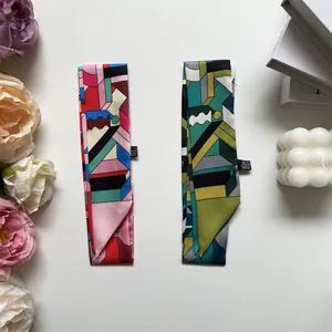 Detail shot of narrow geometric print silk scarves featuring satin texture and side labels