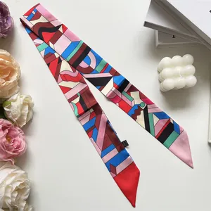 Elegant geometric patterned narrow silk scarf displayed with luxury gift box and flowers