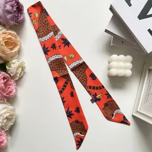 Detail of orange leopard print silk twilly scarf styled with flowers and art decor