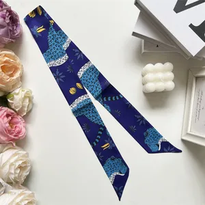 Detail of dark blue silk twilly featuring leopard and floral motifs on a white surface