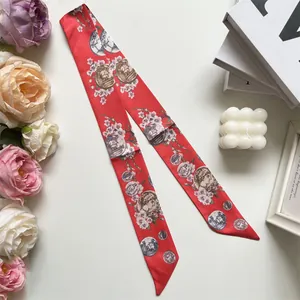 Close-up of red silk twilly scarf with floral prints and vintage coin patterns