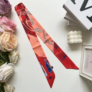 Detailed view of red and orange equestrian print twilly scarf on a white decorative setting
