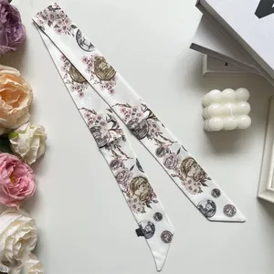 Macro shot of narrow silk scarf with cherry blossom and vintage medal print on books