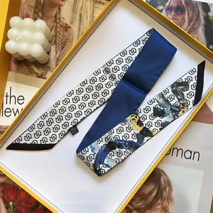 Seidenschal mit blau-weißem Monogramm-Muster in einer luxuriösen gelben Geschenkbox