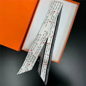Silk twilly scarf with Je vous adore script and heart motif on orange gift box