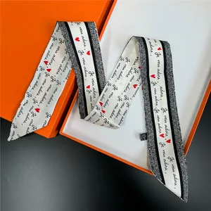 Satin twilly scarf with red heart patterns and love message on an orange gift box