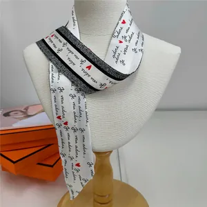 Detail of silk twilly scarf with 'Je vous adore' print and red hearts on a neck model