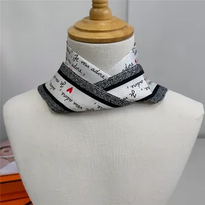 Detail of a white silk twilly scarf with black stripes and red hearts on a mannequin