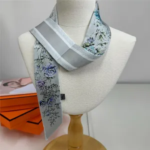 Close-up of floral grey silk twilly scarf tied on mannequin with brand gift boxes