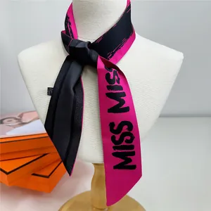Détail d'un foulard en soie fuchsia avec imprimé MISS MISS noué sur un mannequin