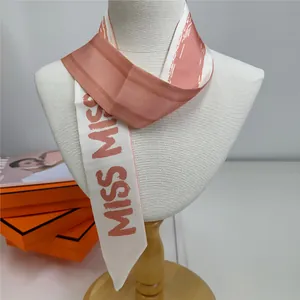 Vue détaillée d'une écharpe en soie rayée sur mannequin avec emballage de marque