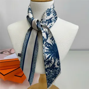 Detailed macro of a blue and white palm leaf print silk scarf with luxury gift box