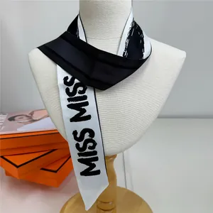 Détail d'un foulard chic en soie noir et blanc avec impression de lettres MISS MISS