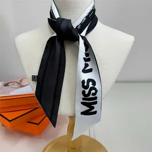 Détail du foulard en soie noir et blanc avec lettrage MISS sur le cou du mannequin