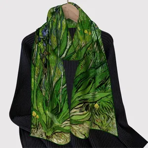 Elegant green leaf print silk scarf displayed on a wooden hanger with a black sweater