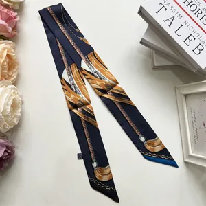 Detailed close-up of dark blue silk twilly with equestrian chain and golden patterns