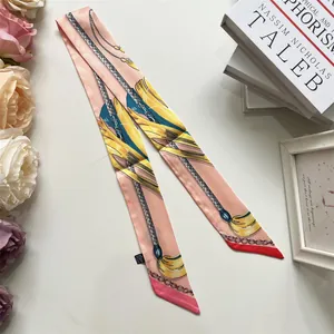 Detailed close-up of pink French ribbon scarf with yellow chain print on soft satin fabric