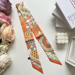 Detalle de un pañuelo estrecho con vibrantes patrones geométricos naranjas y dibujos de abejas
