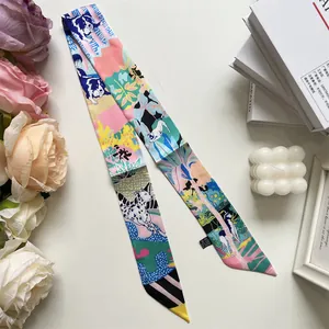 Detail of 100% silk twilly scarf with dog prints and flowers on a white tabletop