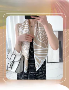 Close-up of elegant beige silk-satin scarf with white leaf patterns worn by a model